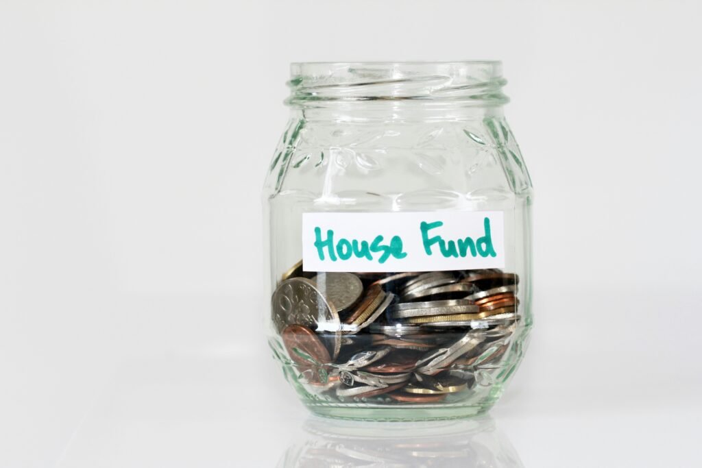 The words House Fund label on a clear glass jar filled with coins